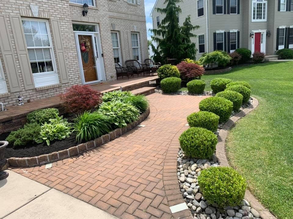 Professionally landscaped South Jersey home with brick walkway, trimmed shrubs, and planting beds