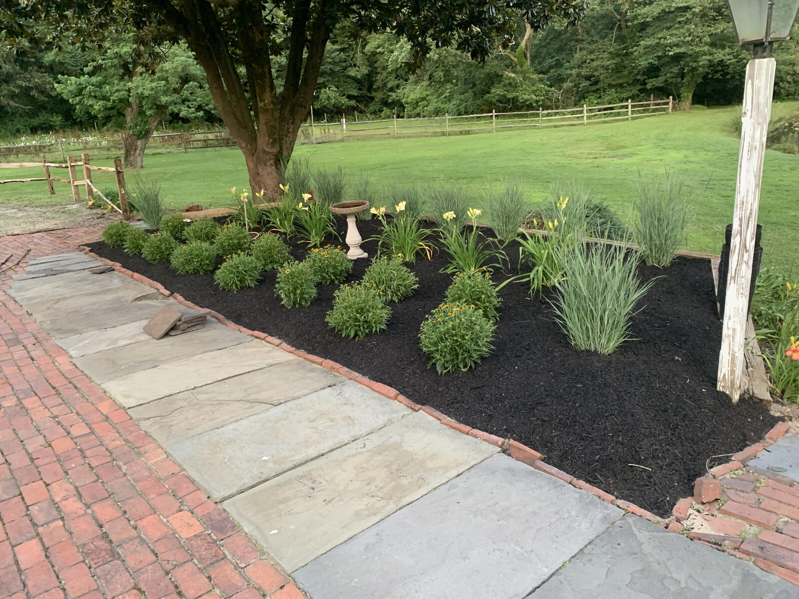 Freshly planted landscape bed beside a stone and brick walkway