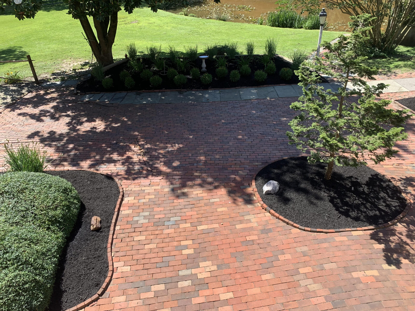 Brick walkway framed by fresh mulch and curved landscape beds