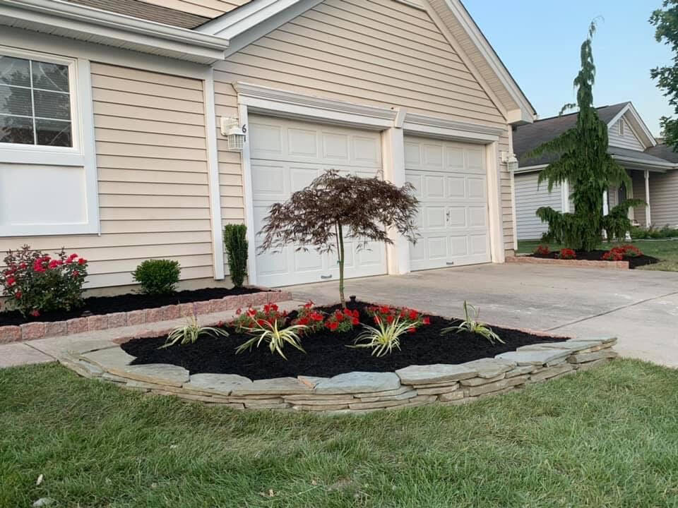 Front-yard landscape bed with natural stone edging and seasonal color